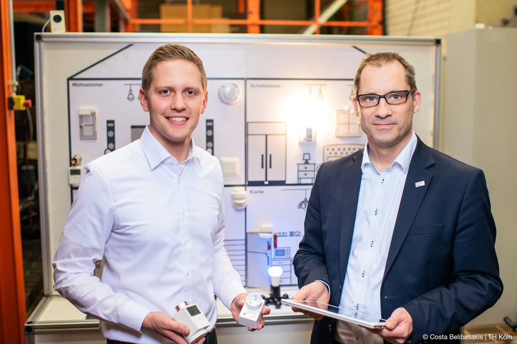 Smart Home-Systeme: Projektteam vor der Smart Home-Wand, mit der sie verschiedene Anwendungen erläutern (Bild: Costa Belibasakis | TH Köln).