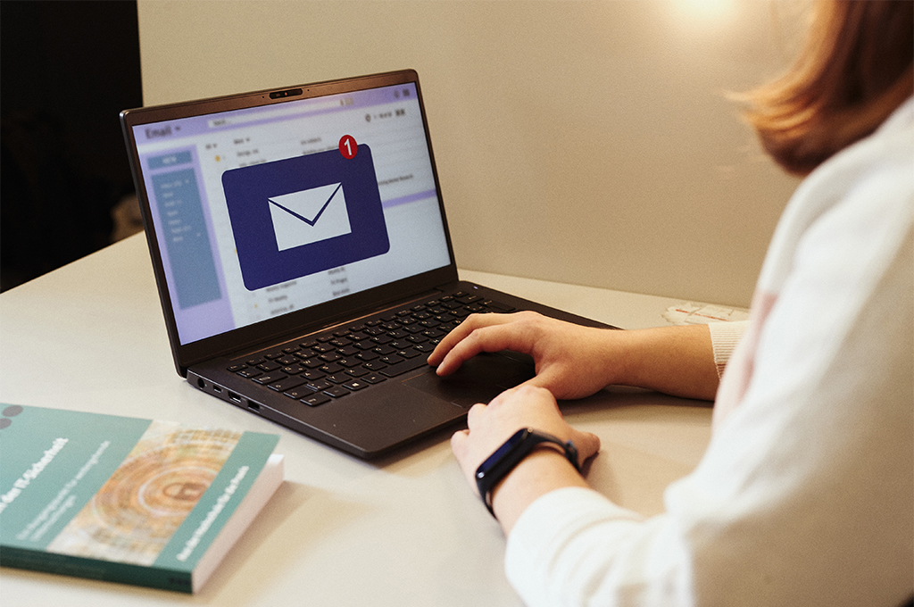 Mensch sitzt vor Laptop und öffnet eine Nachricht.