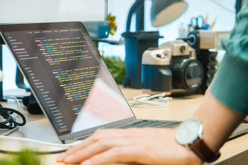 Hand eines Menschen liegt auf Schreibtisch vor Laptop