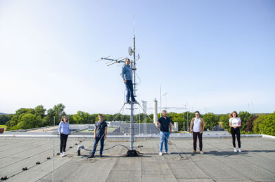 Fünf Studierende bringen auf dem Campusdach einen Sender an